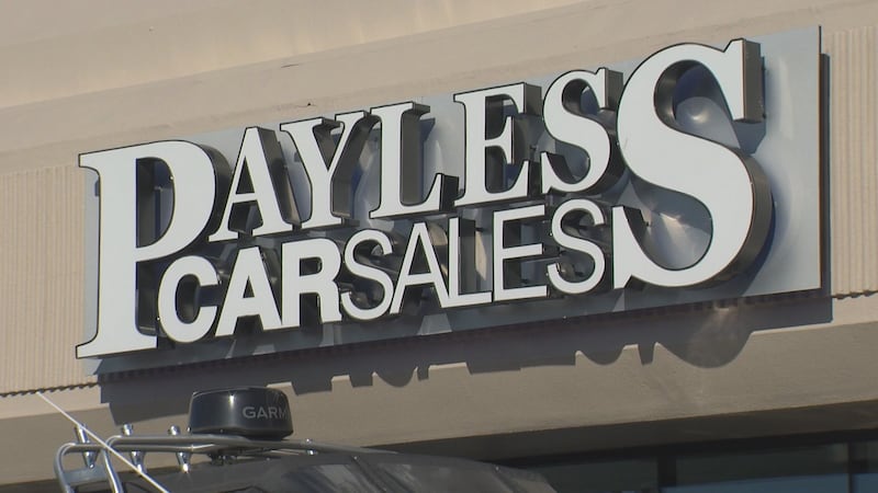 A storefront sign for Payless Car Sales in Anchorage. The dealership has agreed to pay more...