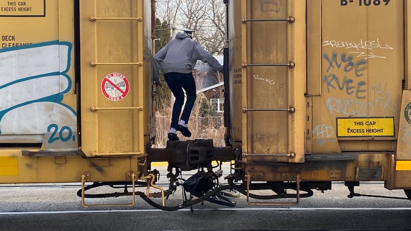 A child jumps between two train cars, going over the coupling between the two pieces of...