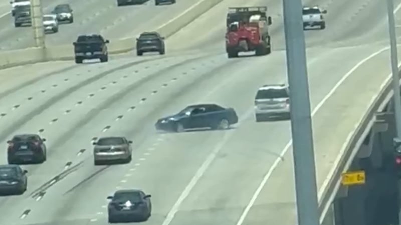 Video of the incident shows a white SUV pulling a blue sedan by a chain. The sedan is facing...