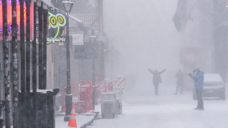 People walk around on Bourbon Street as snow falls in the French Quarter in New Orleans,...