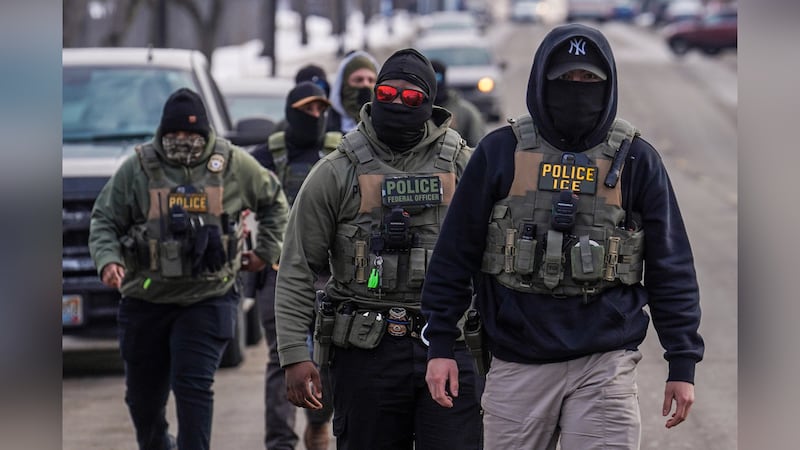 FILE - Federal agents walk down a street while conducting immigration enforcement operations...